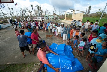Families line up to receive tarps in Barangay Cantariwis in Tolosa, Leyte. Officials try to ensure the most needy receive assistance.