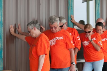 Some of the volunteers who worked on the home pray over it before the dedication ceremony.