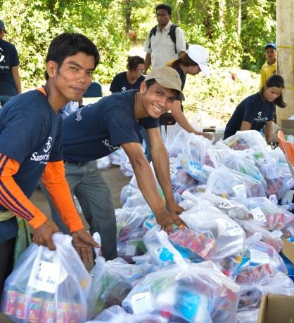 SP team members Panha and Borit help assemble bags of food.