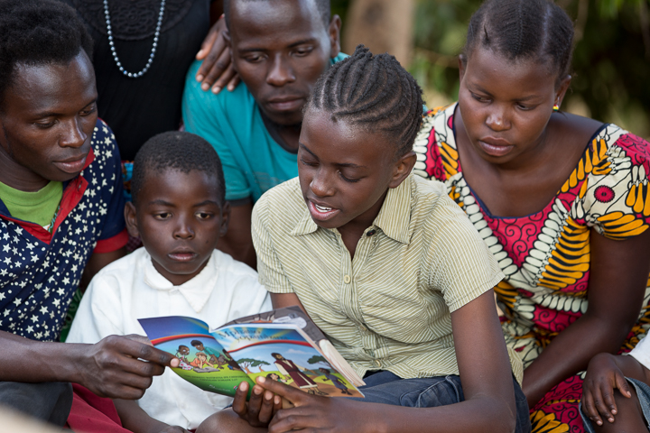 Angella reads the Gospel booklet to her family. All are now following Christ.