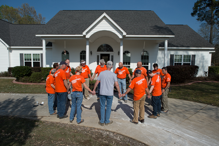 Orange-clad Samaritan' s Purse volunteers pray at the Ogle home in Monroe, Louisiana. 