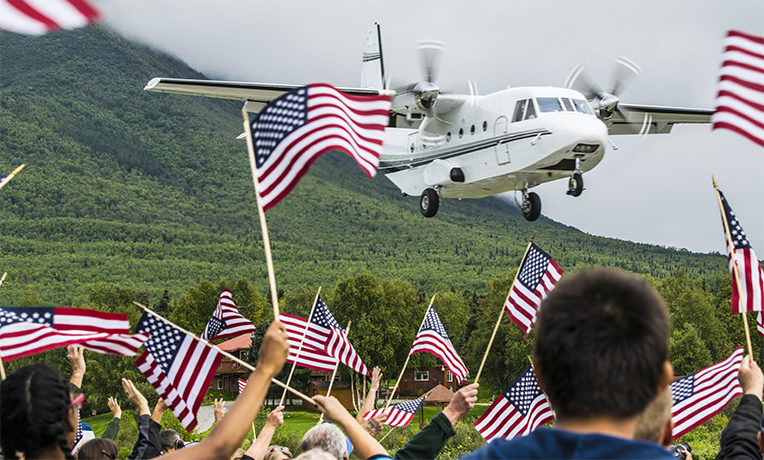 American flags wave to greet Patriot couples. Samaritan's Purse plane lands.