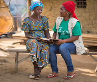 A Samaritan's Purse staff member reads the Bible with Kpanna, a local church leader. Our staff share God's Word before beginning each leadership class.