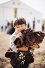 Ammar and Muna's oldest son holds a blanket from Samaritan's Purse.