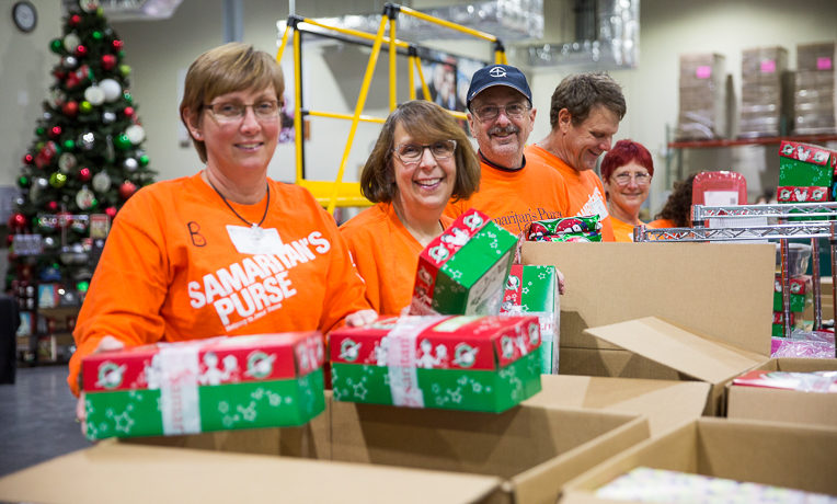 Brenda Evans (left to right), Lori Lybrook, Jeff Reigel, Michael Scales, and Dee Reigel served together processing shoebox gifts for international delivery. [Not pictured: Karen Scales and Leslie Meinen also served.]