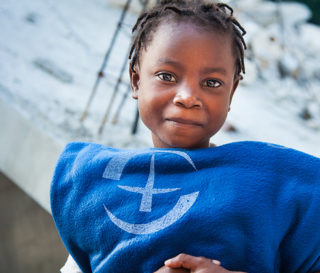 Haitian girl holding blanket provided by Samaritan's Purse