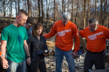 Homeowner Kyle King, with his wife Doreen and son Mick, prays for Samaritan's Purse volunteers who worked on their home.