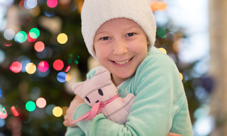 Emma Hemphill abraza uno de los ositos donados y hechos a mano, que ella empacó en las cajas de regalos de Operation Christmas Child.