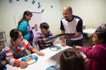 Jesús Valdez serves breakfast at the feeding center that he and his wife, Lucero (back, left), operate.