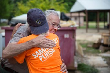 Team leader Patti Fryer hugs homeowner Gary Garrett after volunteers helped him and his wife, Delores, salvage what valuables and keepsakes they could from the house Gary built.