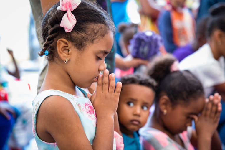 Girl praying at Operation Christmas Child event in the Dominican Republic