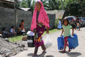 A mother and child carry home their emergency supplies. 