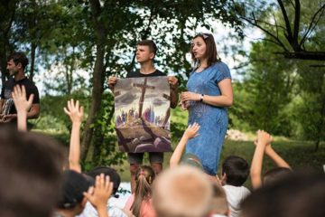 Natalya Bernik shares the Gospel with the children at Golden Generation Camp using posters from the Ministry Partner Guide before the children receive their gifts.