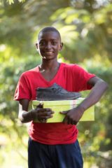 Kwale holds the shoes and box he received them in from Operation Christmas Child.