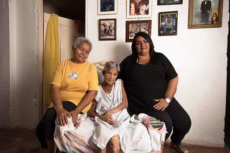 Cecilia Burgos, center, was the first to receive a solar energy relief system at her home. She is joined by daughter Maria Burgos, left, and granddaughter Cecilia Martinez.