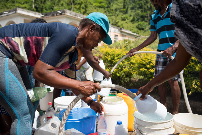 People on Dominica filling water buckets.