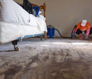 A Samaritan's Purse volunteer vaccuums up the remaining soupy sludge from a flooded bedroom in south Texas.