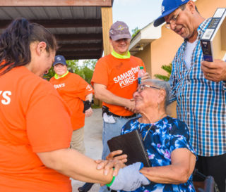 Volunteers present a signed Bible to homeowner Maria Aguirre. Her son, Lupe (right), received Jesus as Lord this week.