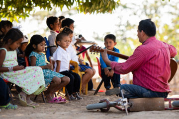 El pastor José Benítez dirige a los niños en una canción y oración en La Laguna, durante su graduación de La Gran Aventura.