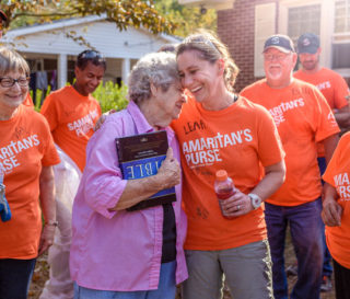 Samaritan's Purse volunteers present Love Whitfield with a Billy Graham Study Bible signed by the team after completing work at her home.