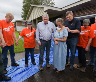 Samaritan's Purse President Franklin Graham prays with homeowner Lorraine Jenkins, flanked at right by Luther Harrison, vice president of North American Ministries for Samaritan's Purse.