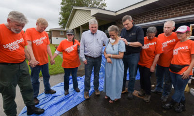 Samaritan's Purse President Franklin Graham prays with homeowner Lorraine Jenkins, flanked at right by Luther Harrison, vice president of North American Ministries for Samaritan's Purse.