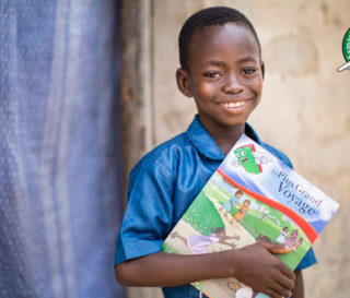 Kevin in Togo holding The Greatest Journey booklet