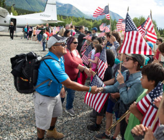 Army Sergeant Larry Kaibetoney and his wife Chani are greeted by flag waving crowds at Samaritan Lodge Alaska.