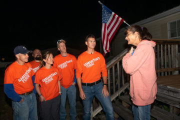 Volunteers present a Bible to homeowner Linda Kelley after repairing her home.