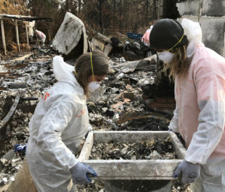 Volunteers sift through ashes at a home destroyed by wildfire in Paradise, California.