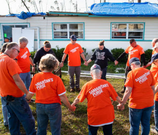 Kara (center, in black) prays with Samaritan’s Purse volunteers before they begin working on her home that was destroyed by Hurricane Michael.