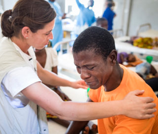 Kelly Sutor prays with patient Agusto Americo who was injured after Cyclone Idai ripped through Mozambique.