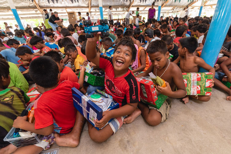 Children are excited to show off their shoebox gifts during a well-attended outreach event.