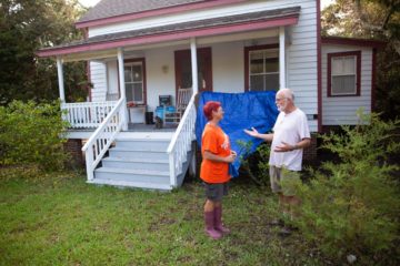 Philip Howard speaks with a volunteer outside of his home.