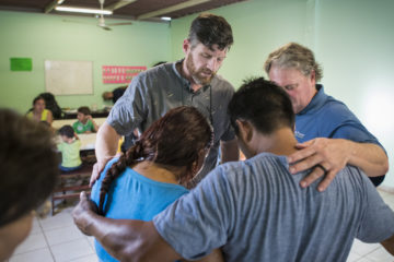 Edward Graham leads a prayer for Jesús at the feeding center.