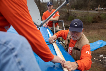 Samaritan's Purse Disaster Relief volunteers place heavy duty tarp on the tornado-damaged roof of Alonzo and Sarah Lee Thompson.