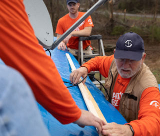 Samaritan's Purse Disaster Relief volunteers place heavy duty tarp on the tornado-damaged roof of Alonzo and Sarah Lee Thompson.