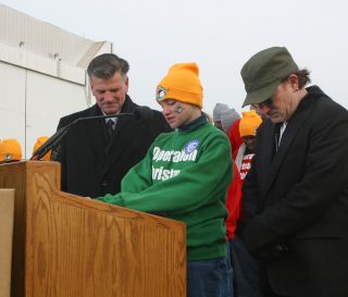 Lesley Clementi flanked by Franklin Graham (left) and musician Bono (right) pray during a special send-off for Operation Christmas Child shoebox gifts being airlifted to Uganda.