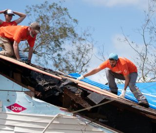 Samaritan's Purse volunteers patch a roof at the home of Garrison Worthington where hurricane winds sent a large oak crashing through.
