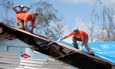 Samaritan's Purse volunteers patch a roof at the home of Garrison Worthington where hurricane winds sent a large oak crashing through.