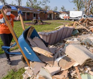 Woman working to clear debris after hurricanes in Louisiana.