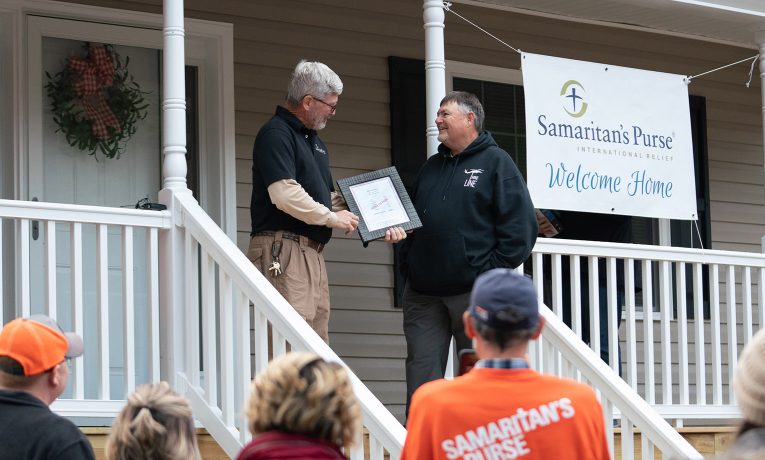 Andy Beauchamp, the Samaritan's Purse Whiteville area rebuild project superintendent, presents Michael Register with a "Paid in Full" plaque at the dedication of his new home.