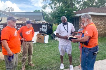 Volunteers present a Bible to Tony DeVille after completing work on his home.