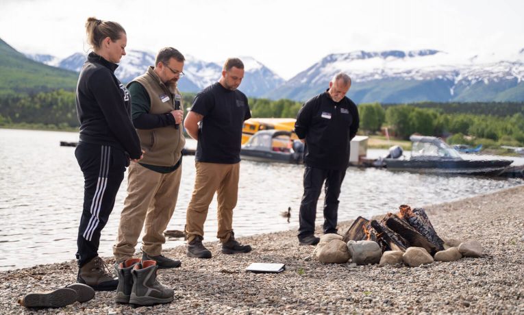 Trish Dawson joins her husband and our chaplains in prayer being baptized in Lake Clark.
