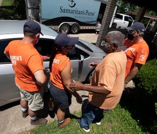 Homeowner Rufus Goodwin gathers with volunteers to pray outside his Lake Charles home.