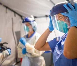 Medical staff prepare for each shift with personal protective equipment and prayer.