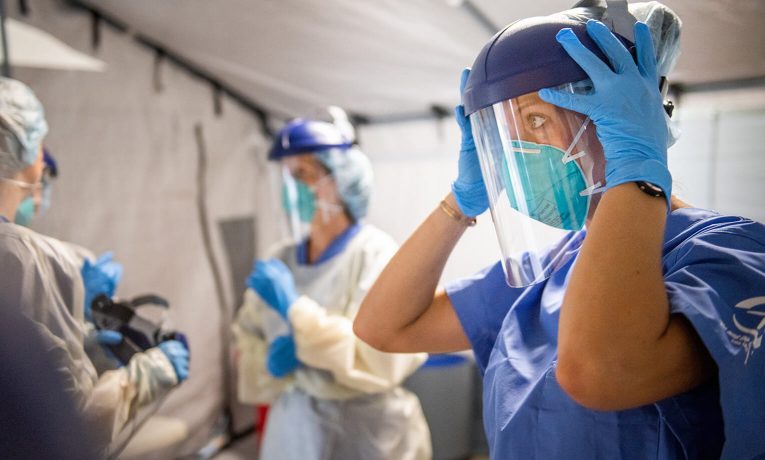 Medical staff prepare for each shift with personal protective equipment and prayer.