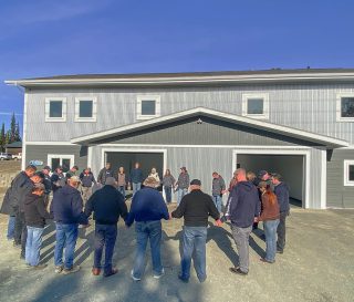 Staff, volunteers, and leaders from Amundsen Educational Center gather around the completed student housing to pray for future students and the school.