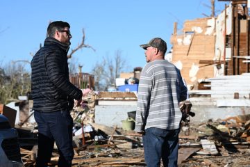 Edward Graham hears the story of Marty Janes. He and his wife were trapped in their home after the tornado devasted their community.