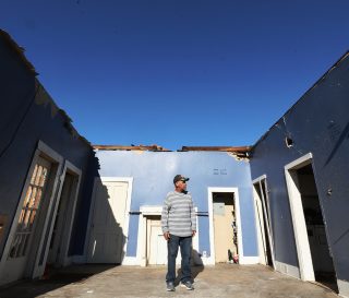 Marty stands in the living room of his now-roofless house. He and his wife were were rescued from its rubble the night of the deadly tornadoes.